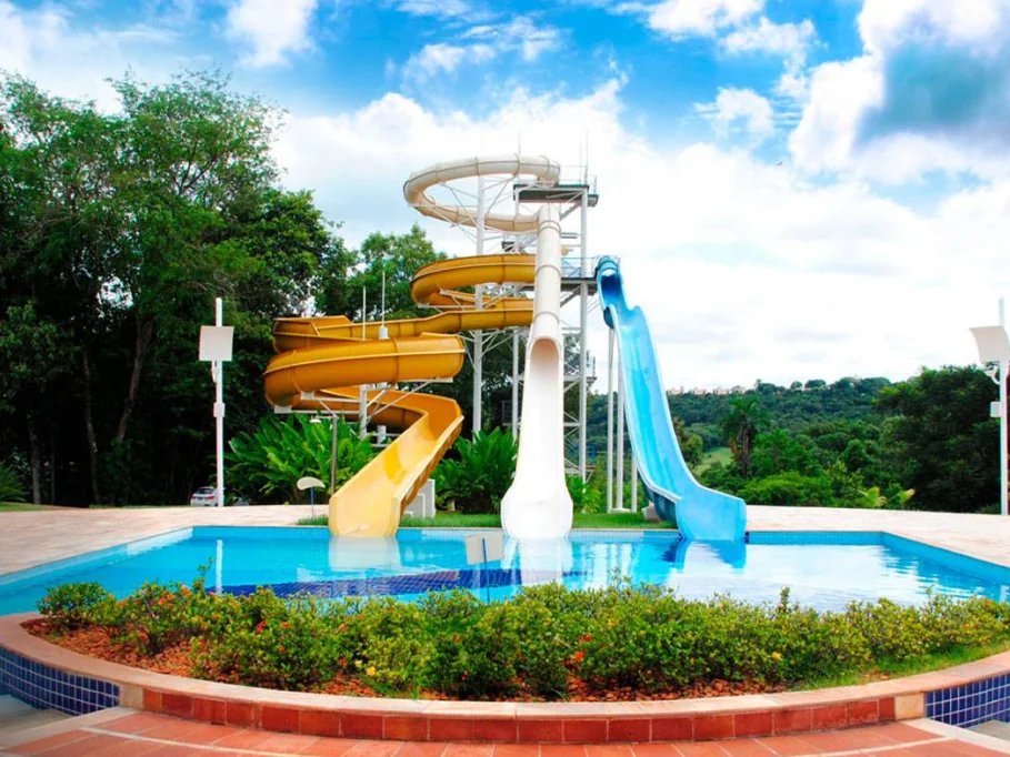 Torre de toboáguas amarelos e azuis do Aguativa sobre uma piscina com jardim