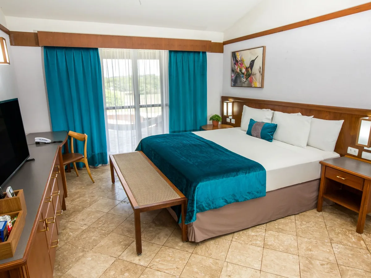 Apartamento Superior do Blue Tree Lins com cama de casal, TV e cortinas azuis