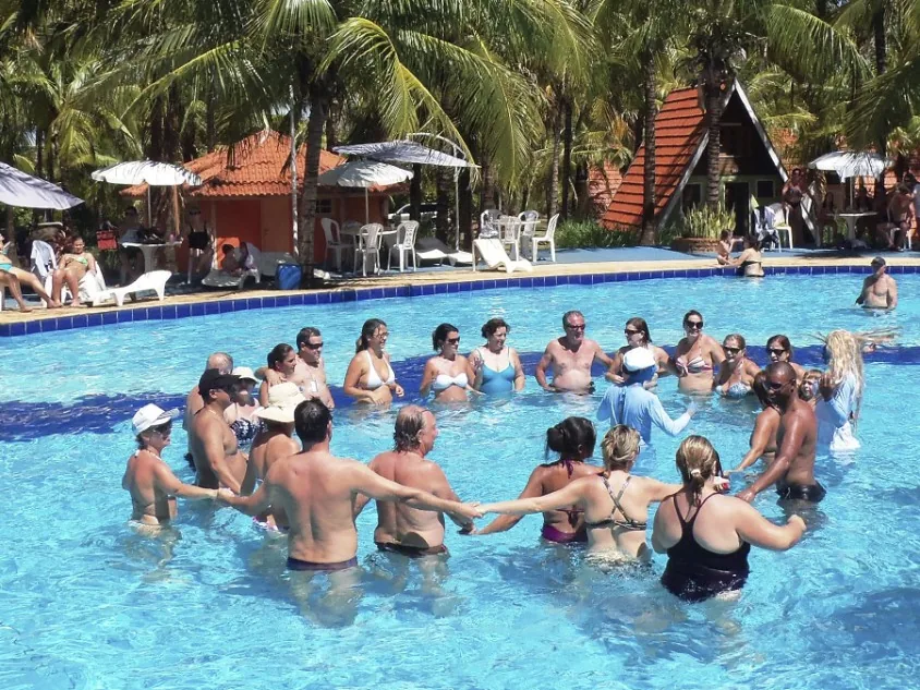 Hóspedes de mãos dadas numa roda de recreação dentro da piscina do Campo Belo