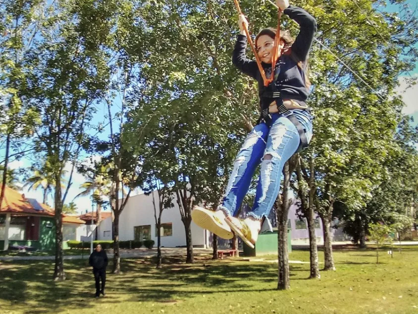 Hóspede descendo na tirolesa entre as árvores do Campo Belo