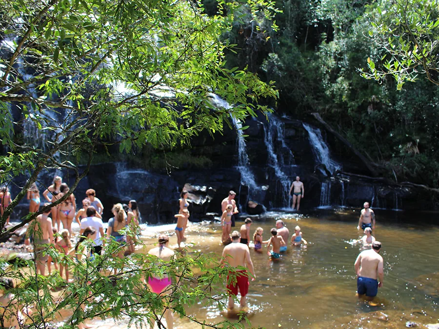 Hóspedes tomando banho no poço de uma cachoeira da reserva do Itáytyba