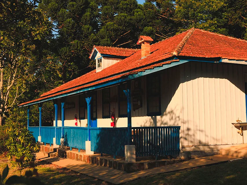 Casa de madeira restaurada da Casa de Memórias Nhá Tota, com varanda azul
