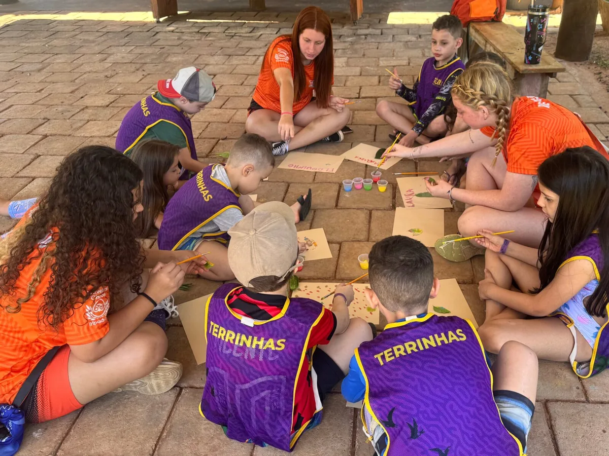 Crianças da turma Terrinhas pintando no chão com as recreadoras do Terra Parque