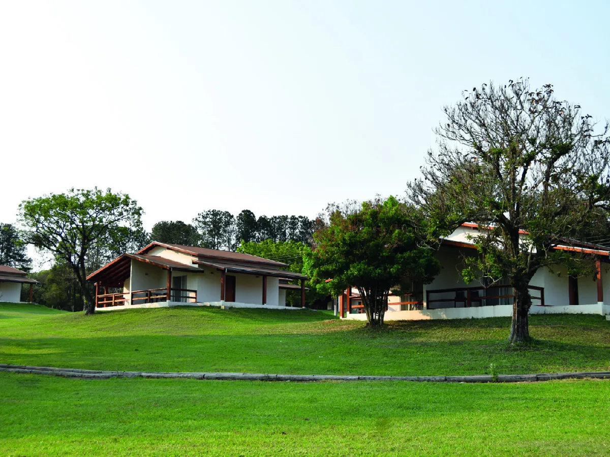 Chalés do Vale das Águas espalhados pelo gramado, entre árvores