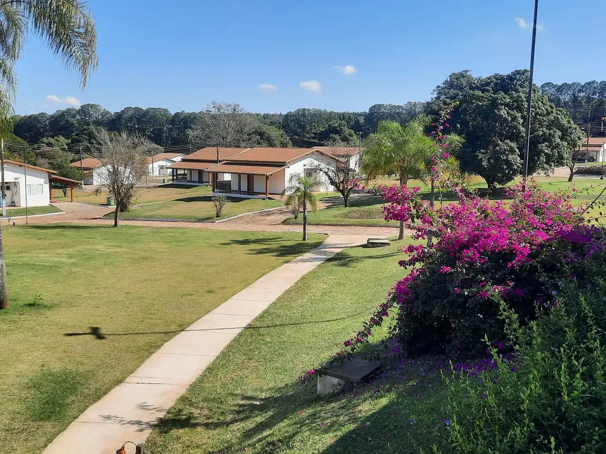 Caminho no jardim do Vale das Águas, com buganvílias e chalés ao fundo
