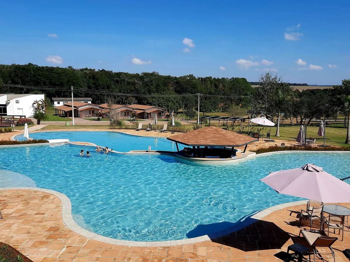 Piscina de desenho orgânico do Vale das Águas, com quiosque no meio e chalés ao fundo