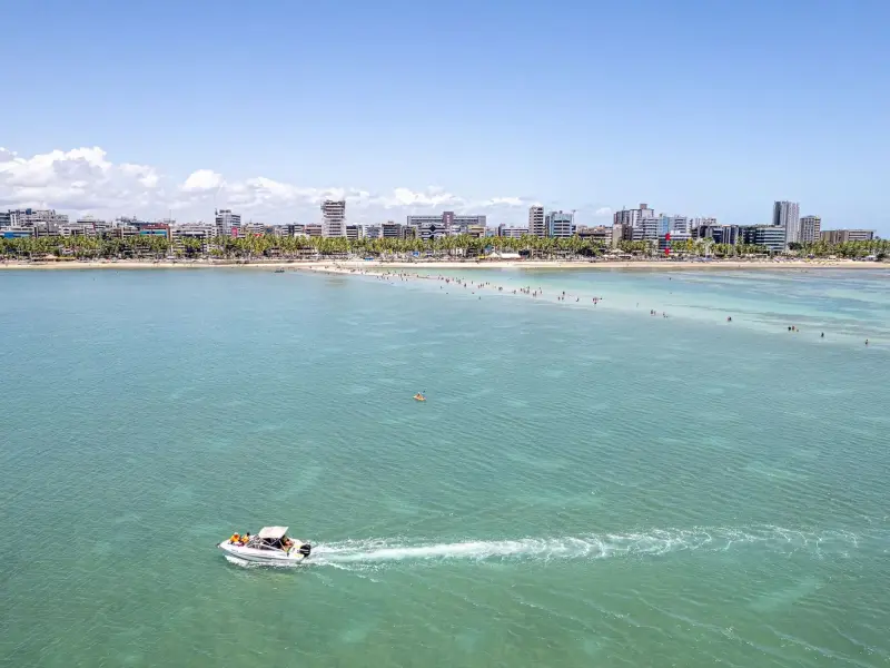 Vista aérea de barco no mar de águas verdes da orla de Maceió
