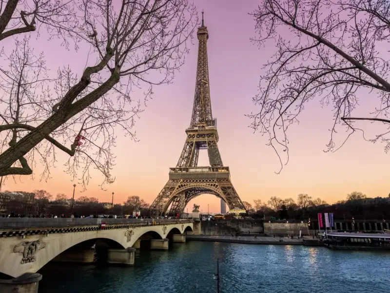 Torre Eiffel iluminada ao entardecer, vista da ponte sobre o rio Sena, em Paris