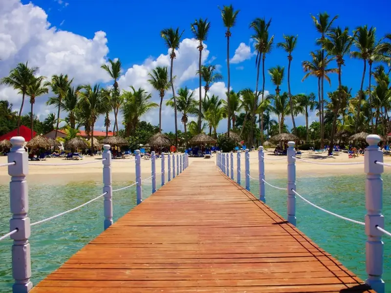Píer de madeira entre coqueiros e mar de águas claras, em Punta Cana
